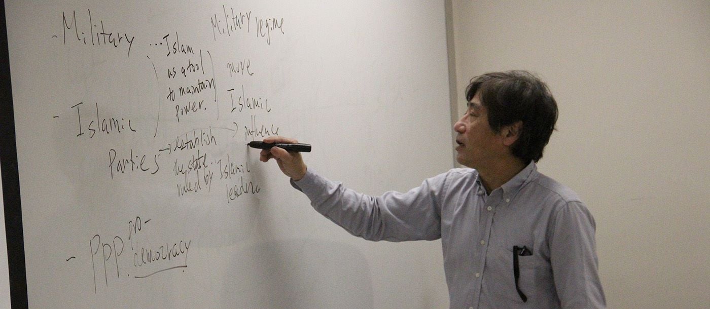 A professor writing on the white board in the classroom during a lecture