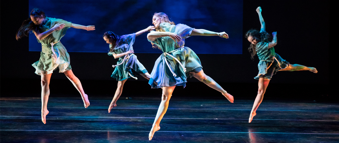 Four dancers performing in stage in a low light environment